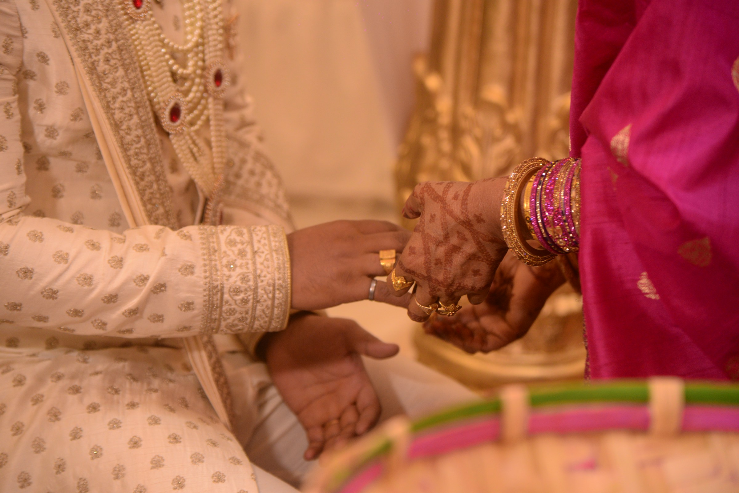 A bride's hennaed hand resting in the groom's hand during the ceremony