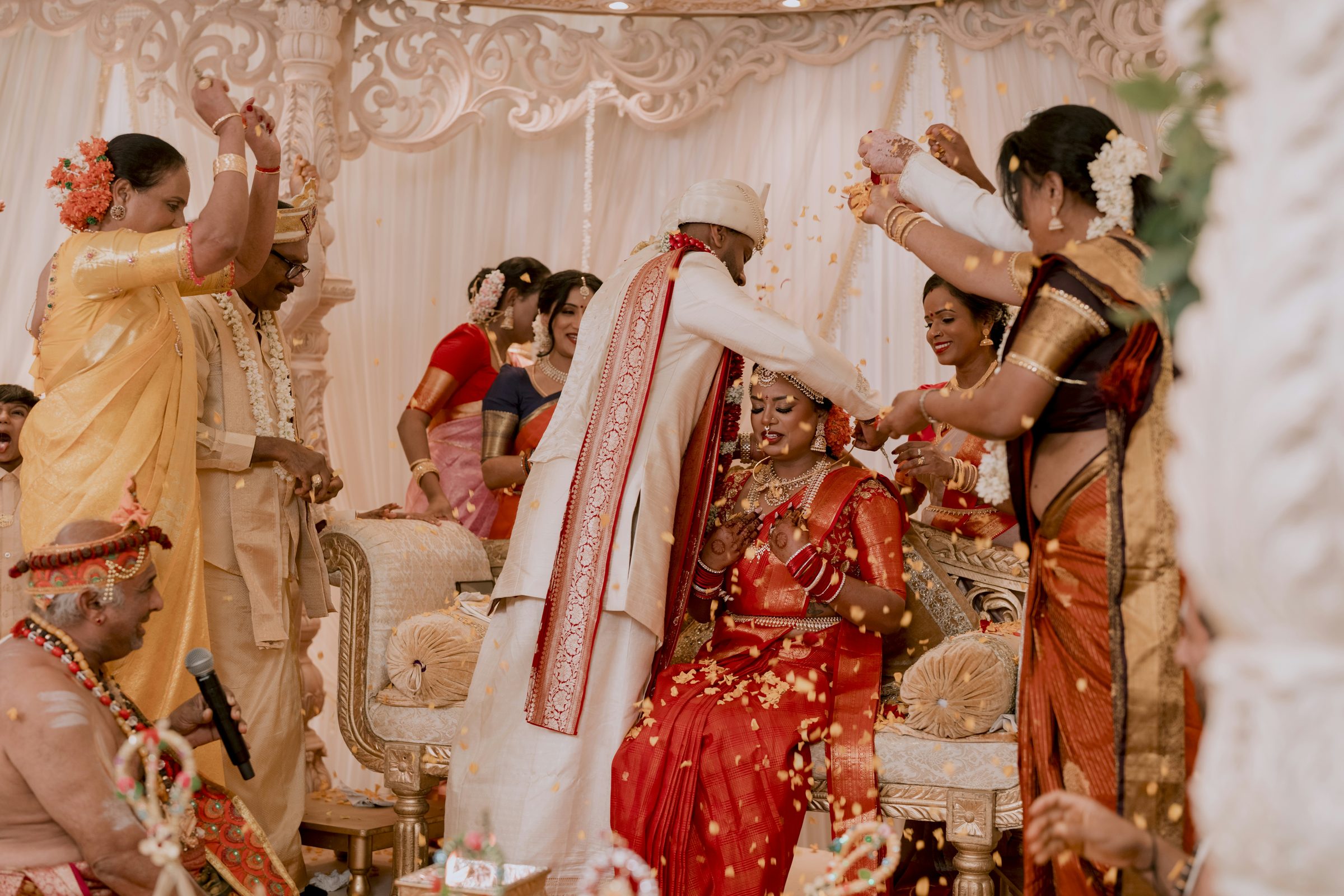 The groom places a veil over the bride's head while family members look on