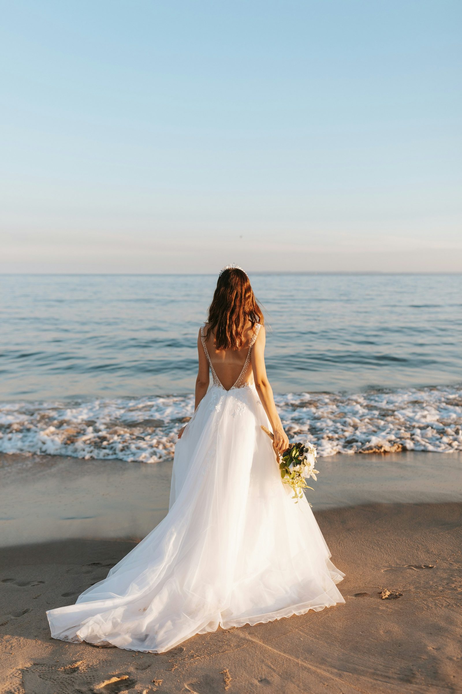 A bride looking out at the sea, holding her bouquet