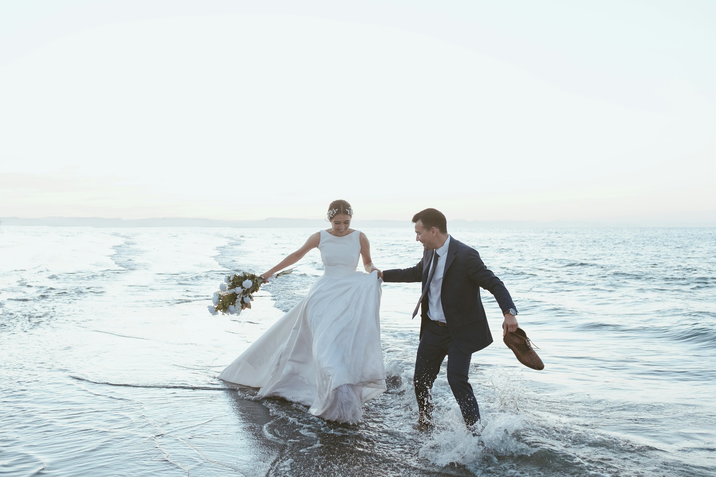 Amélie and Thomas running through the lagoon in their wedding clothes